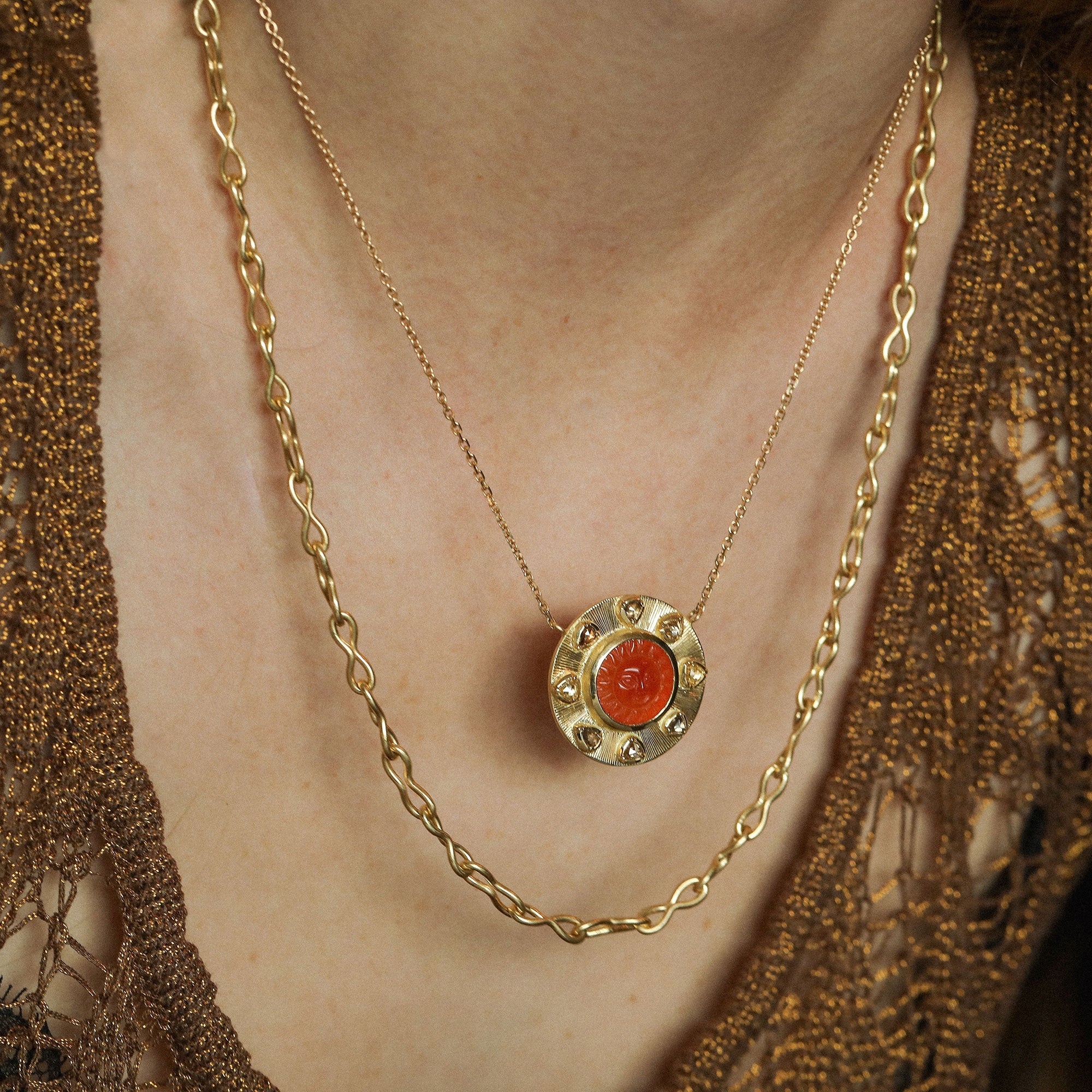 Close up of model wearing 18k gold chain link necklace and one of a kind carnelian and diamond sun necklace from Los Angeles jewelry designer Brooke Gregson