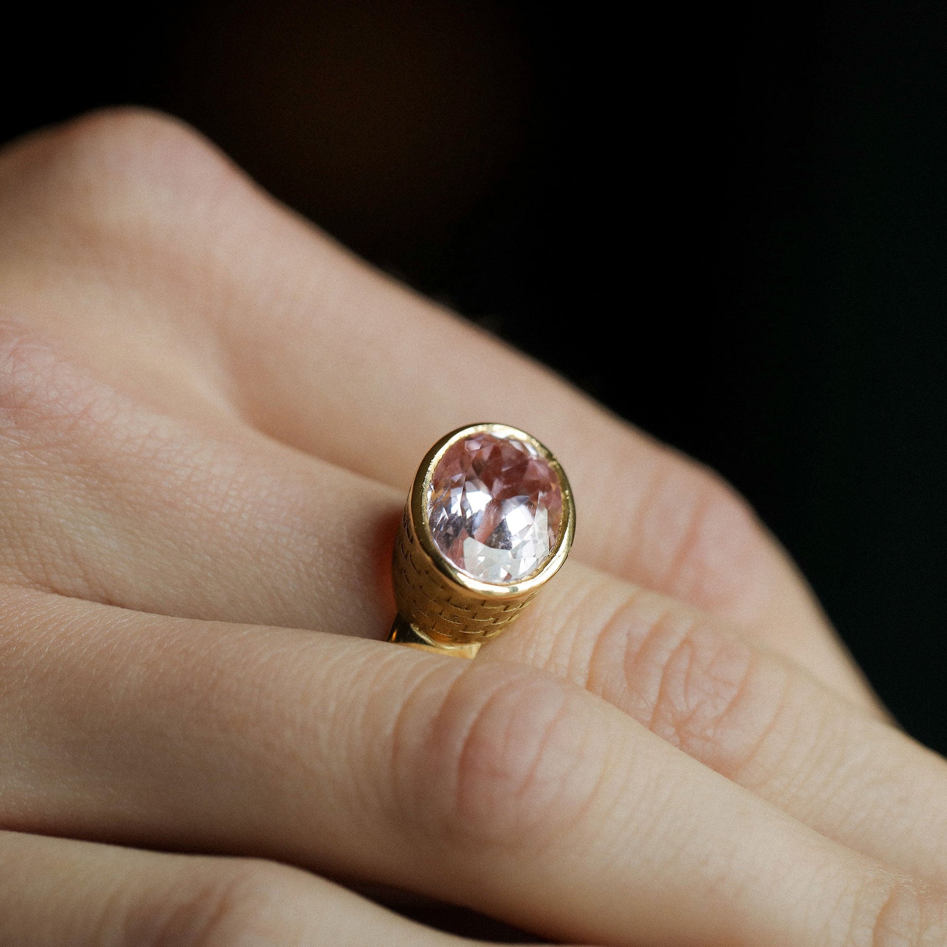 Close up of model wearing one of a kind 18k gold kunzite ring with basket weave engraved setting and bushed gold band from Los Angeles jewelry designer Brooke Gregson