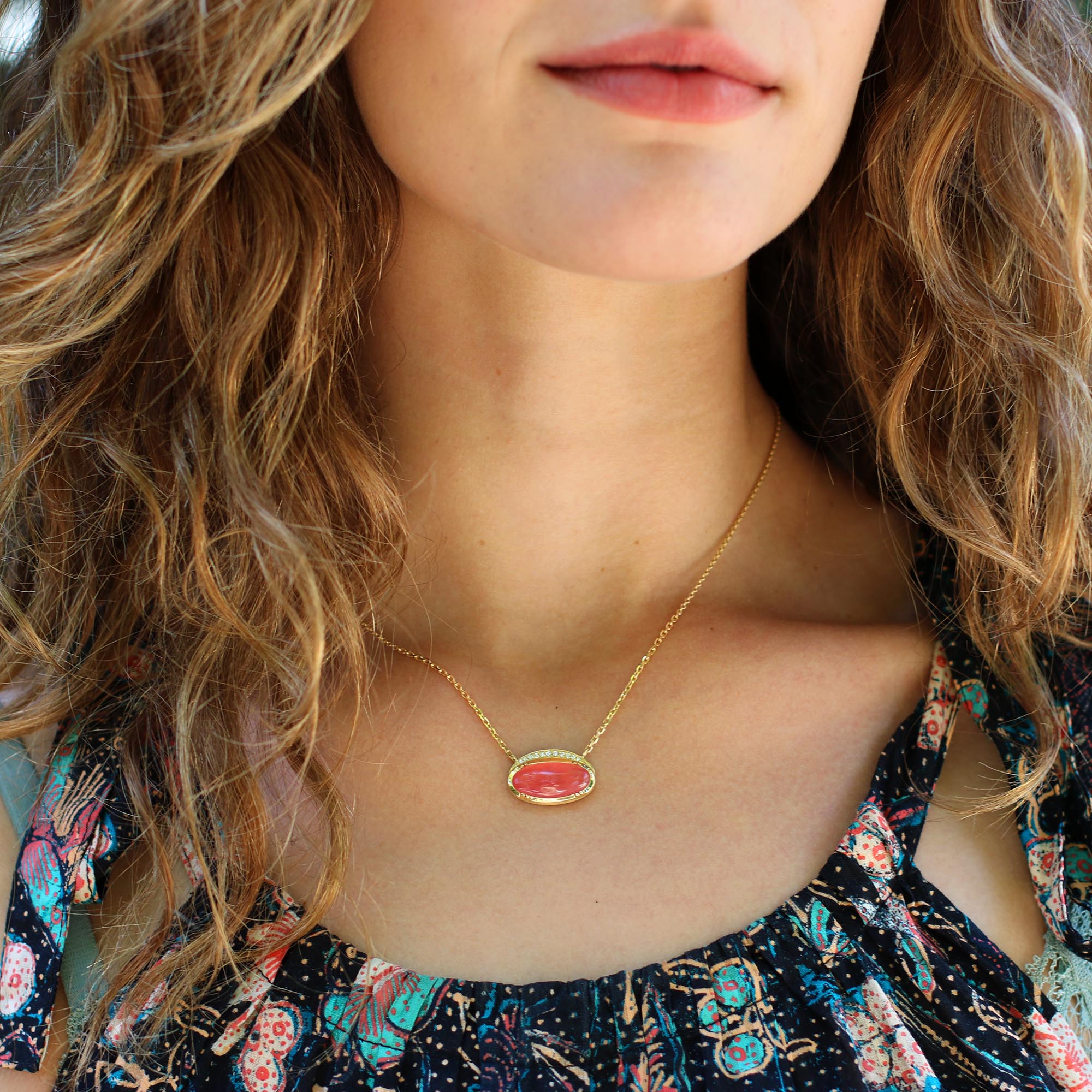 Model wearing one of a kind 18k gold necklace with central oval Rhodochrosite surrounded by a halo of white diamonds from Los Angeles jewelry designer Brooke Gregson