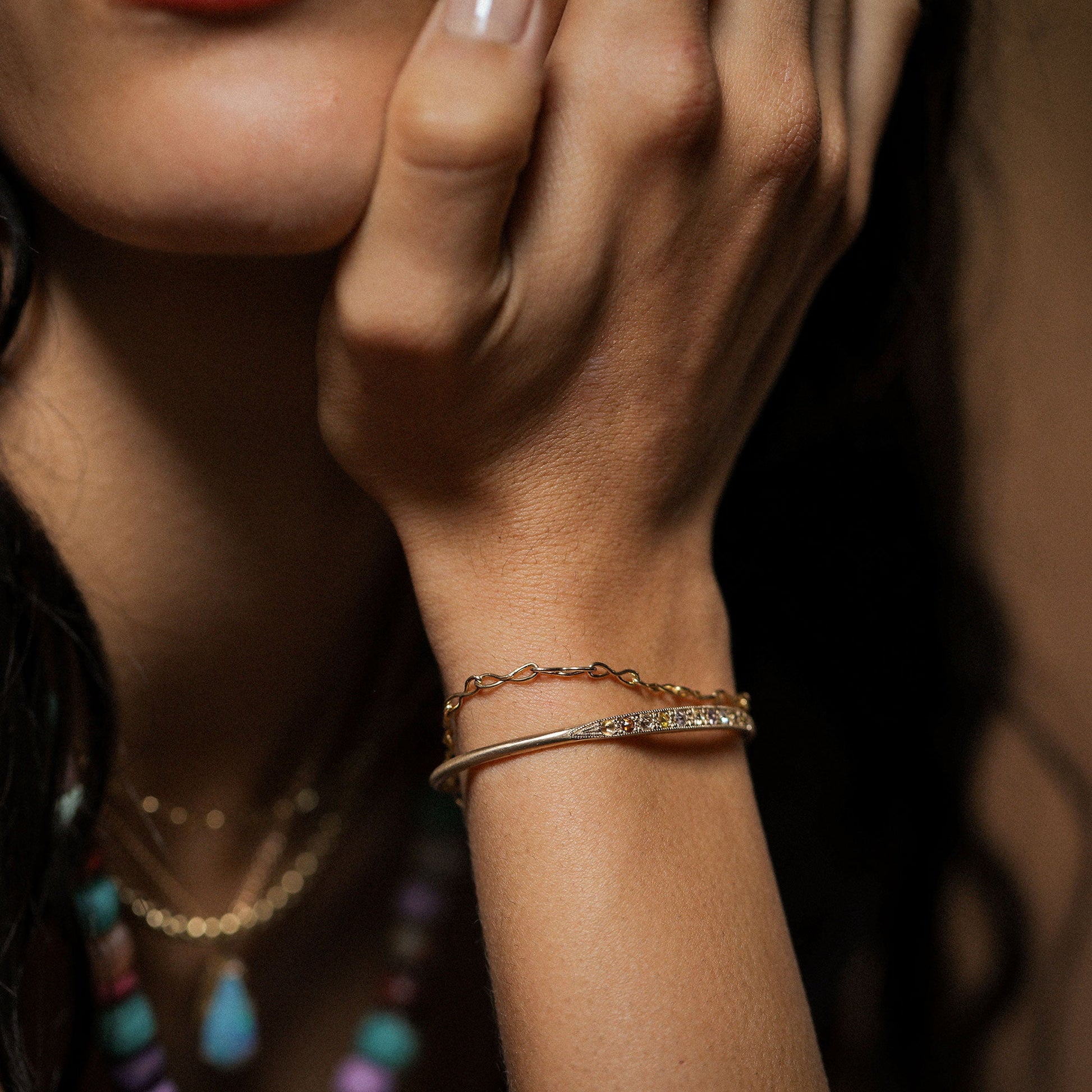 Girl wearing a fine chain link 18k gold bracelet and a cuff with mixed rosecut diamonds by Brooke Gregson.