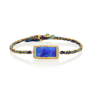 Silk bracelet with blue boulder opal stone and gold chain on a white background