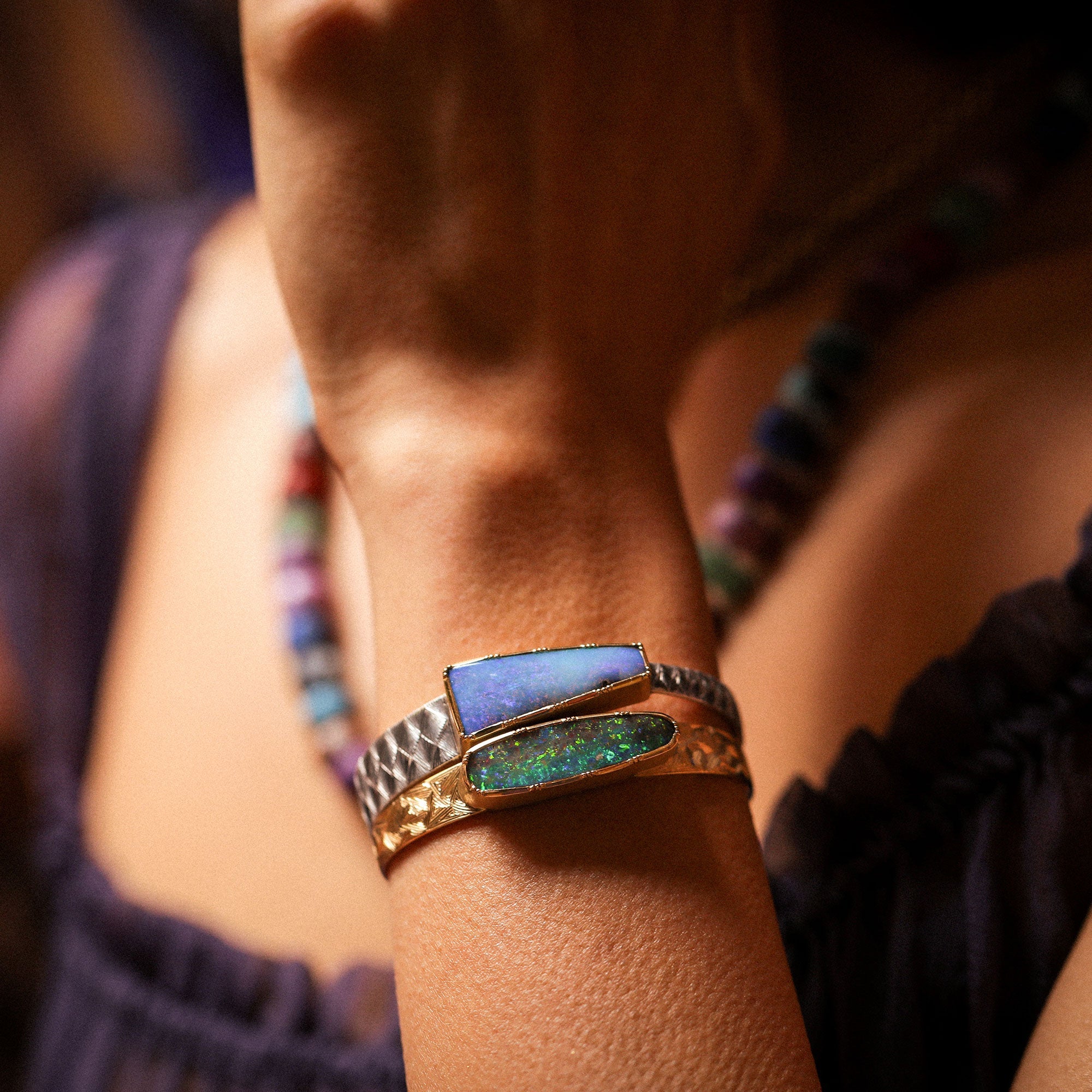 Close-up of a person's arm wearing a colorful opal cuff bracelet.