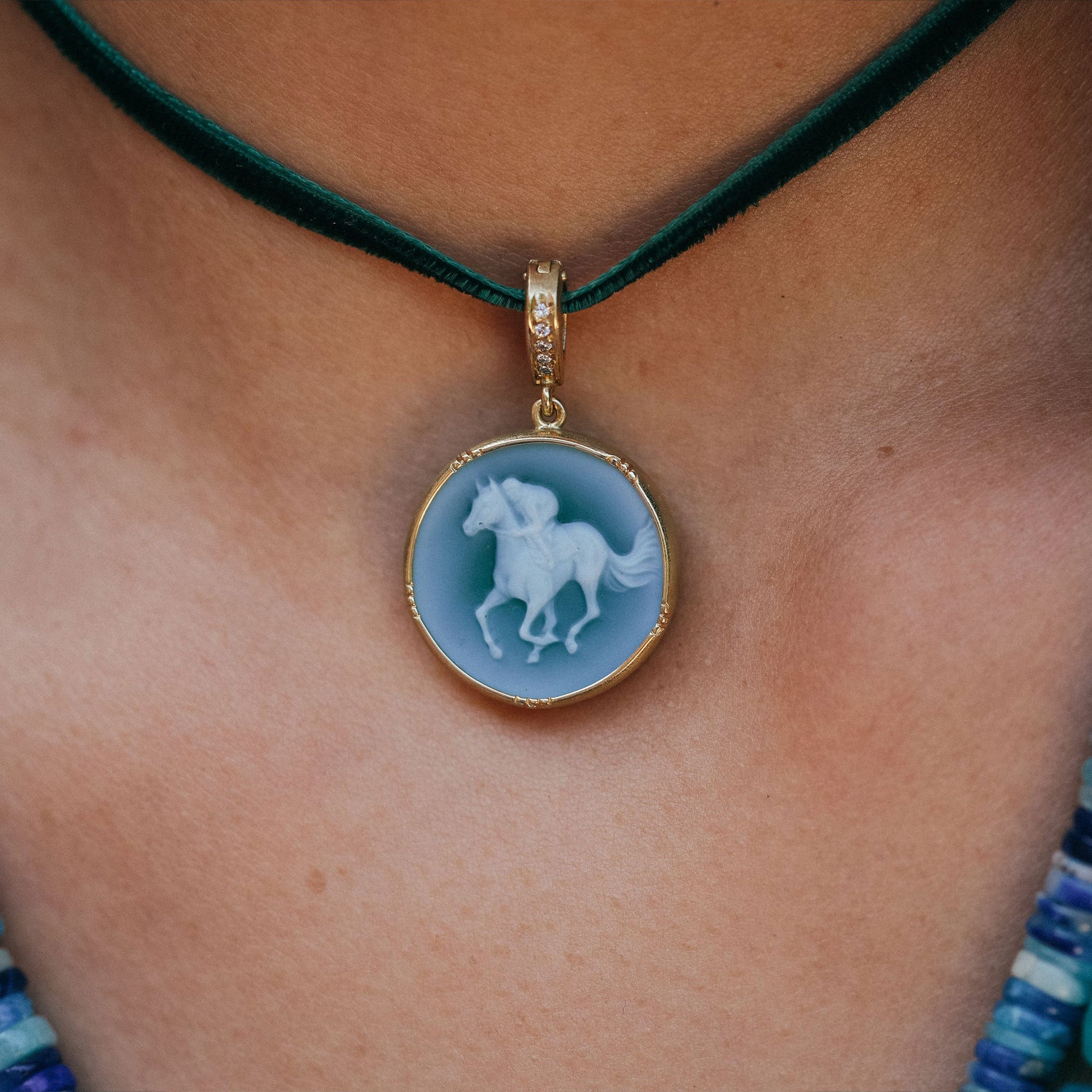 Up close photo of a woman wearing a green velvet Necklace with a pendant featuring an agate horse design