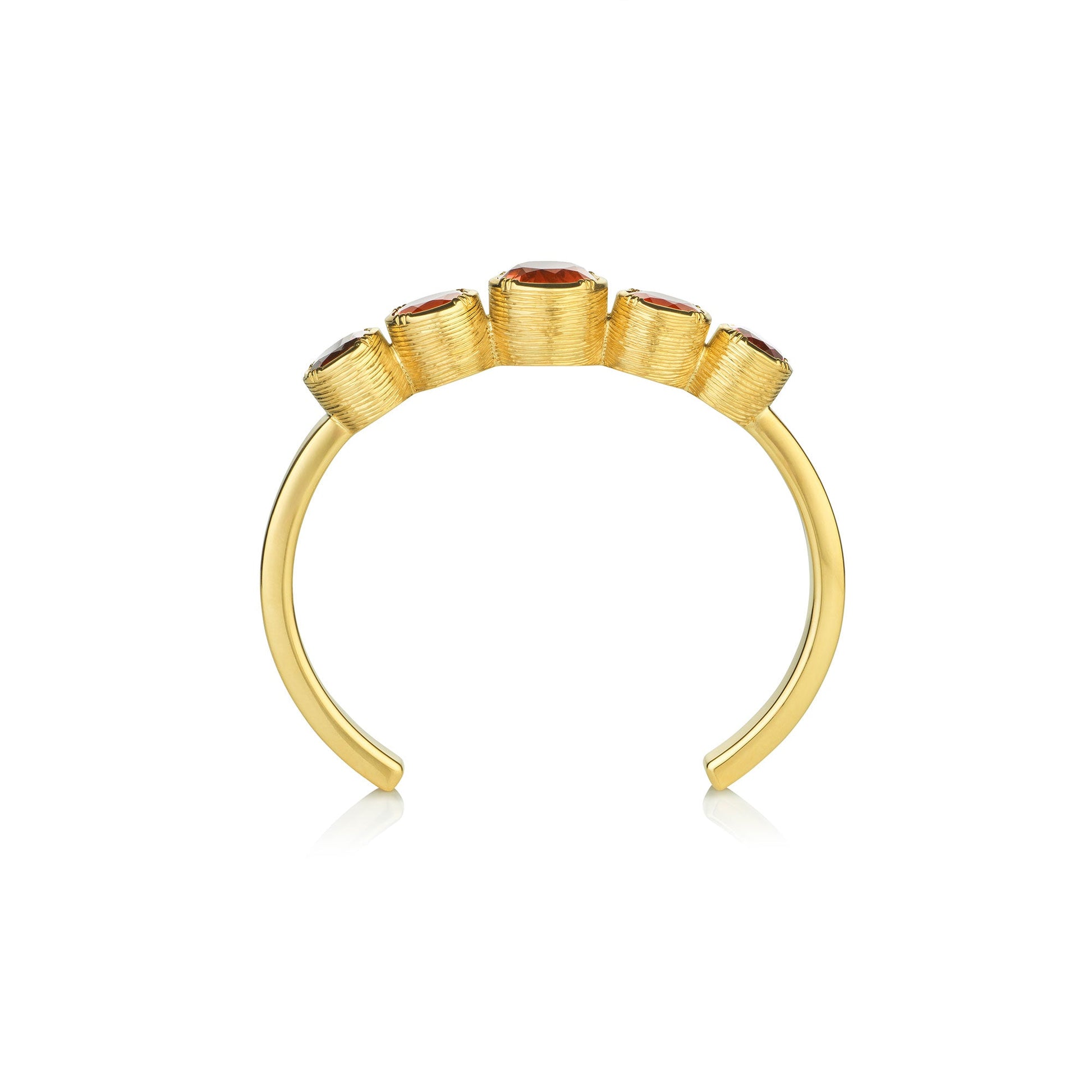 side view of a gold hand engraved cuff with fire opal garnets and tourmalines on a white background.