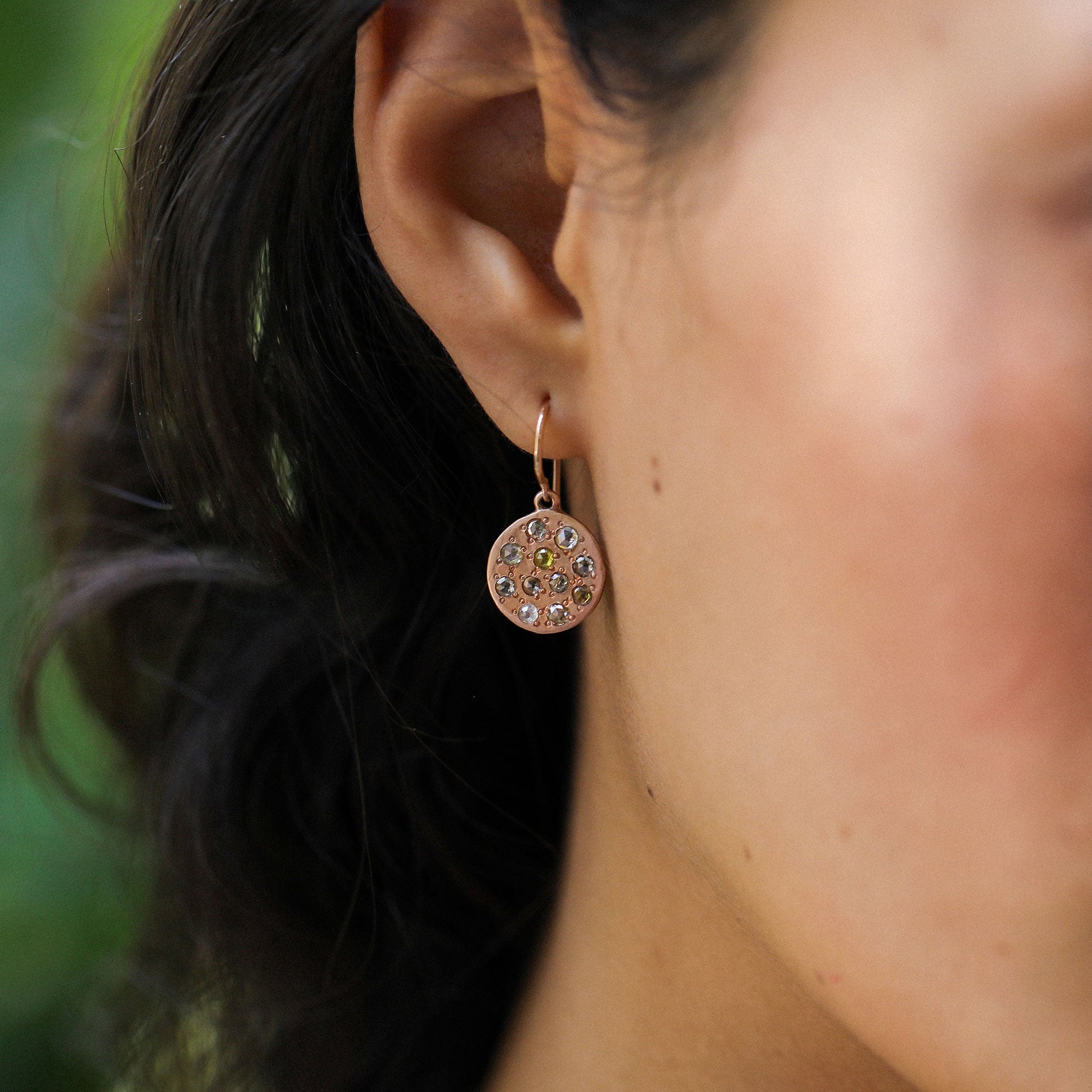 close up of ear wearing a 14k brushed rose gold earring with 11 mixed rosecut diamonds.