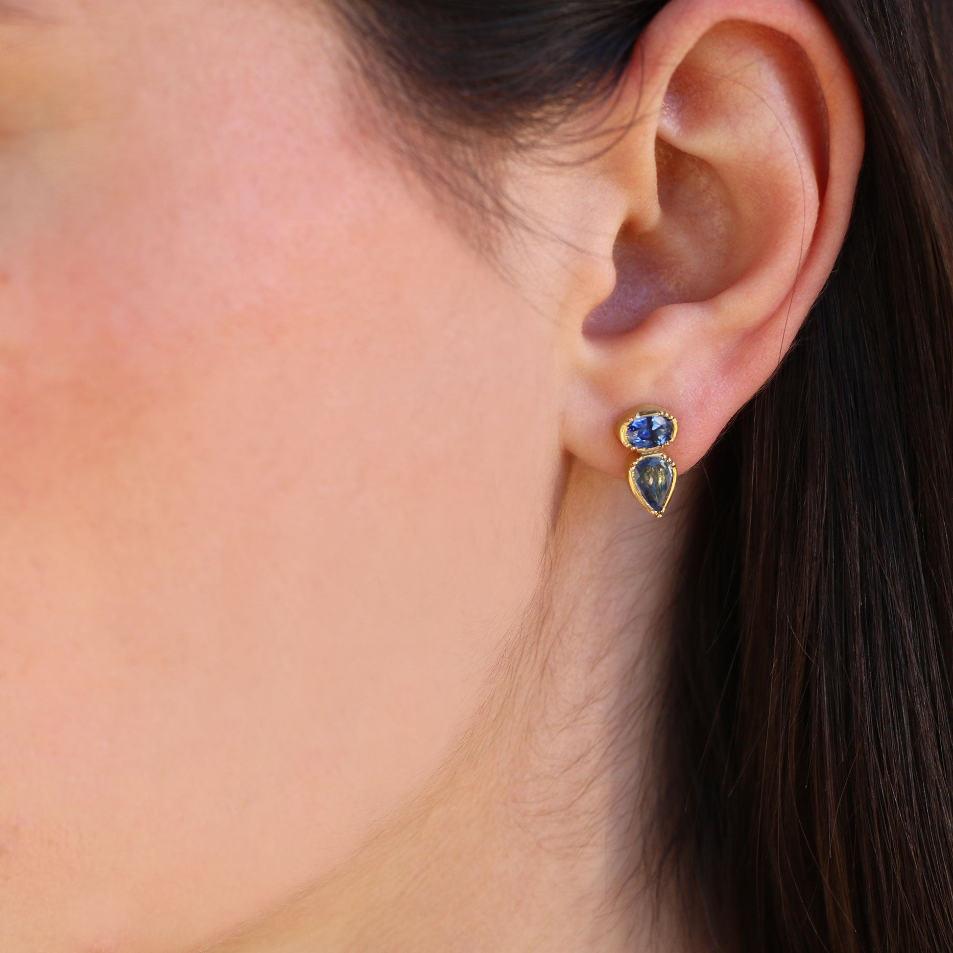 Girl wearing sapphire stud earrings with pear drop