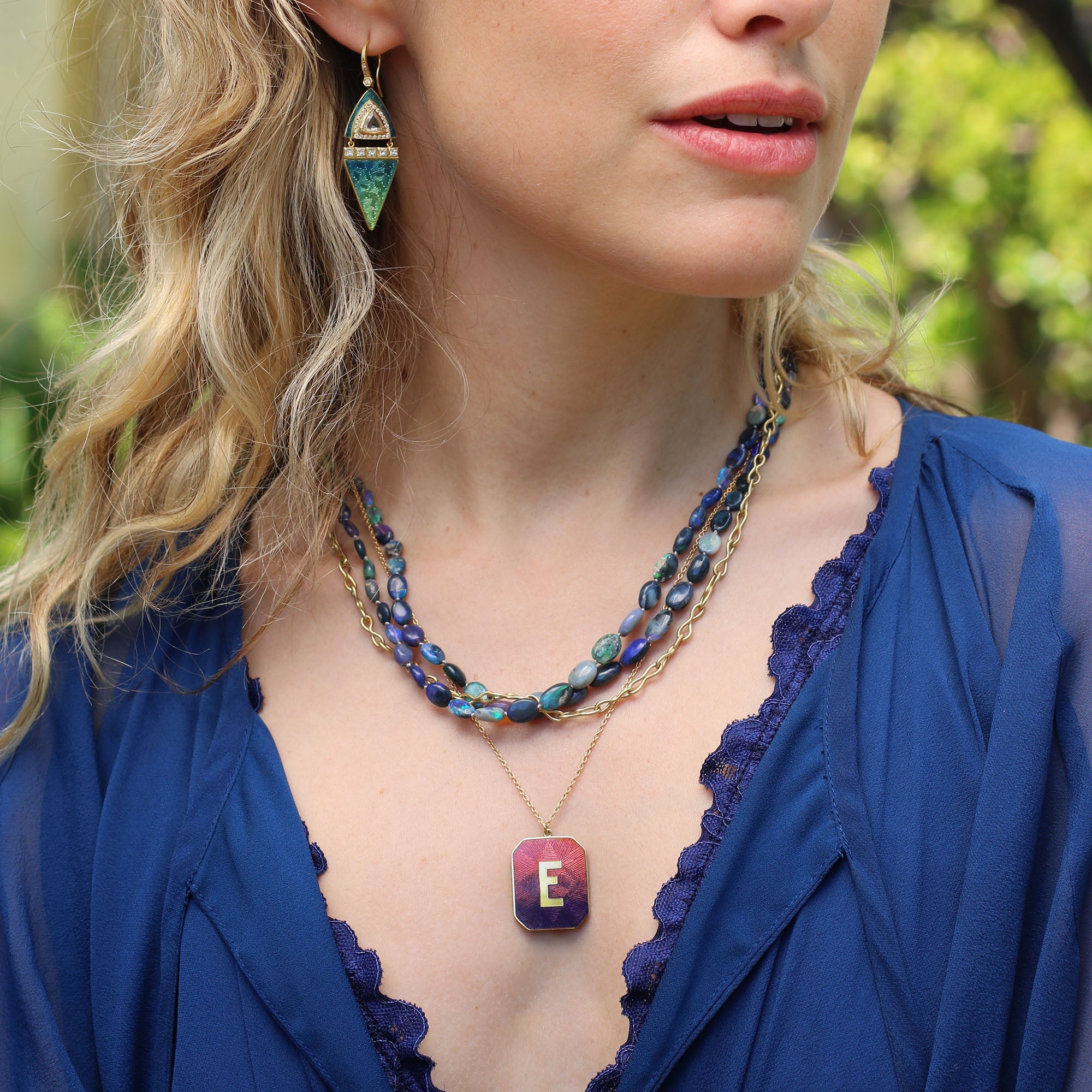Model wearing various jewelry, 18k gold Alphabet Sunset Enamel Letter Necklace by Los Angeles fine jewelry designer Brooke Gregson handmade in London