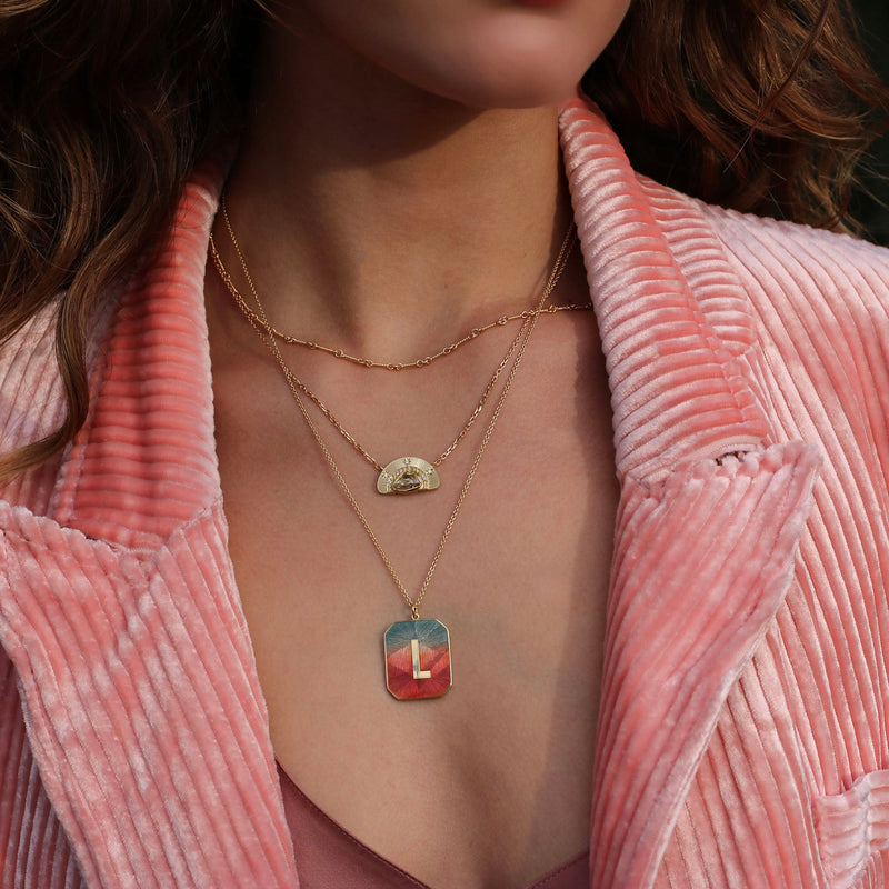 Model wearing 18k gold Alphabet Sunrise Enamel Letter L Necklace by Los Angeles designer Brooke Gregson handmade in London