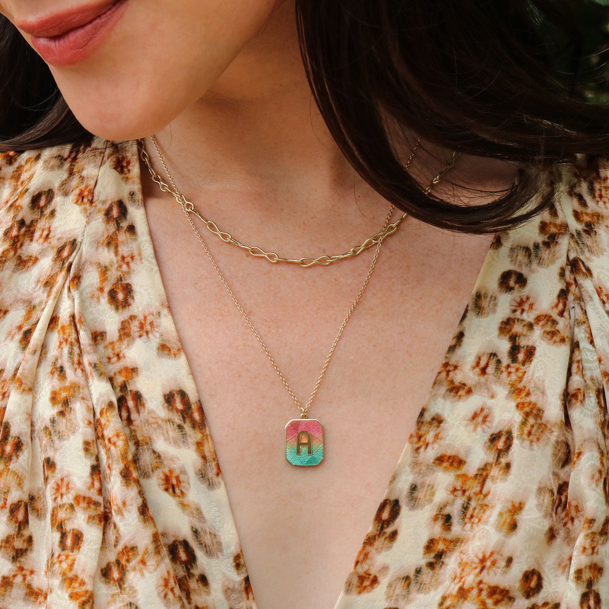 Girl wearing an 18k gold necklace with enamel pendant with letter A on it handmade by jewelry designer Brooke Gregson.