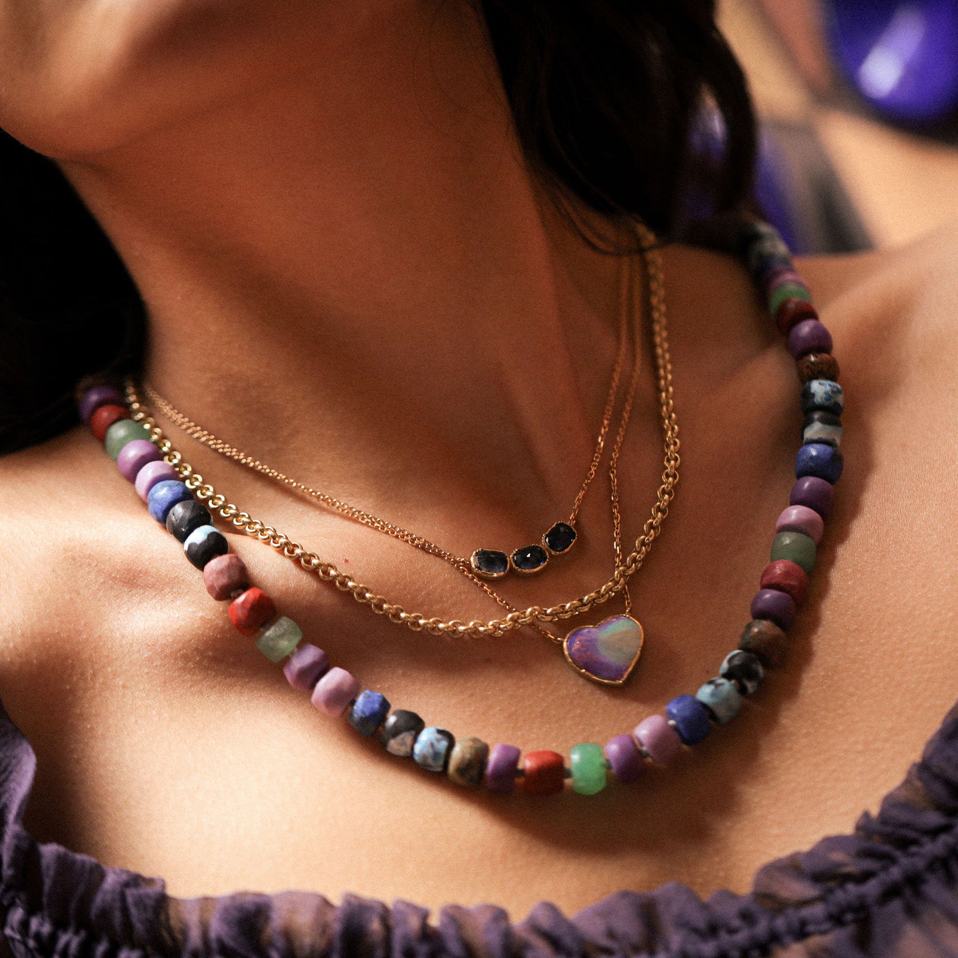 Close-up of a person wearing a colorful beaded necklace and gold chain.