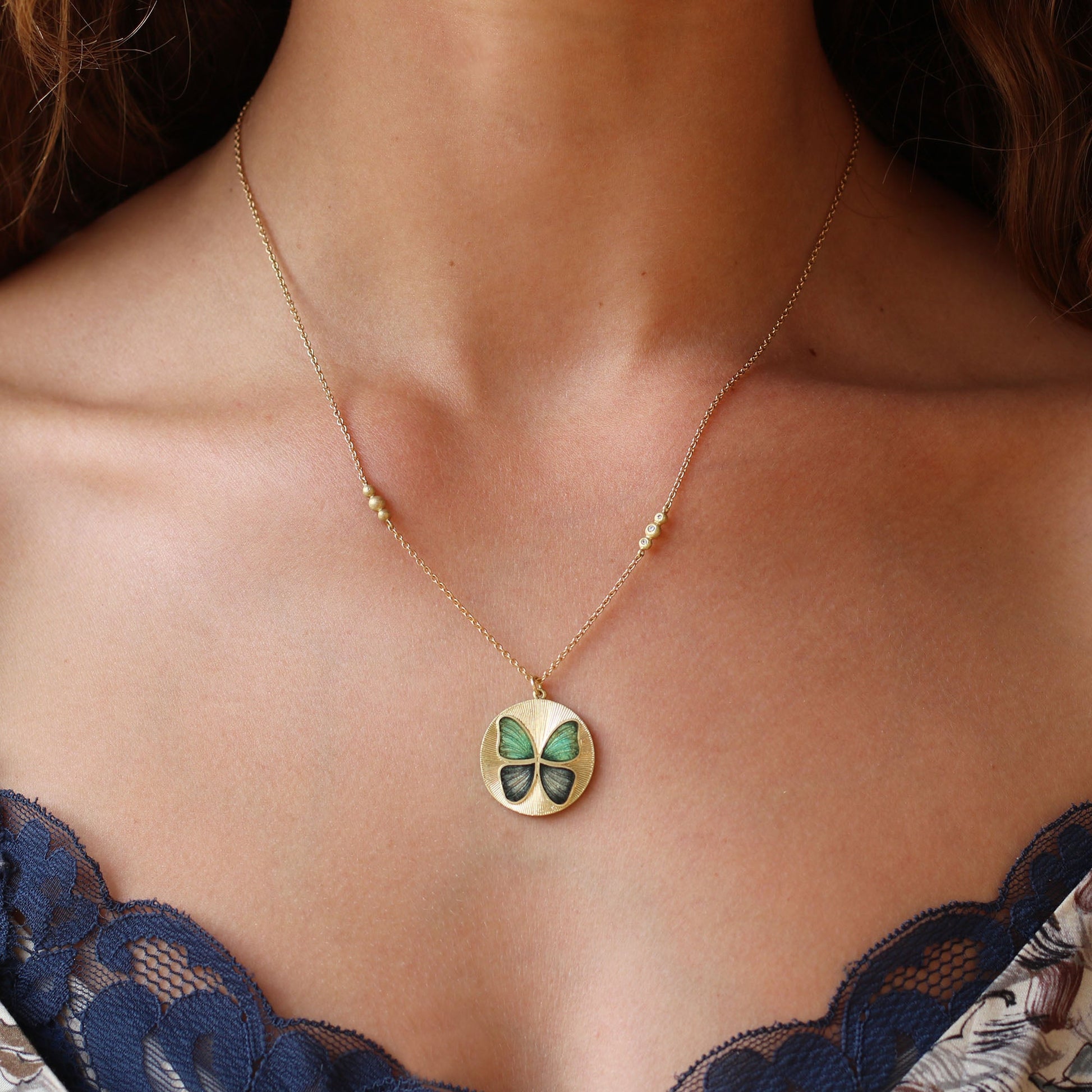 Model wearing Handmade Enamel 18k gold green and blue butterfly enamel necklace with hand engraving Fine jewelry hand made in London. 