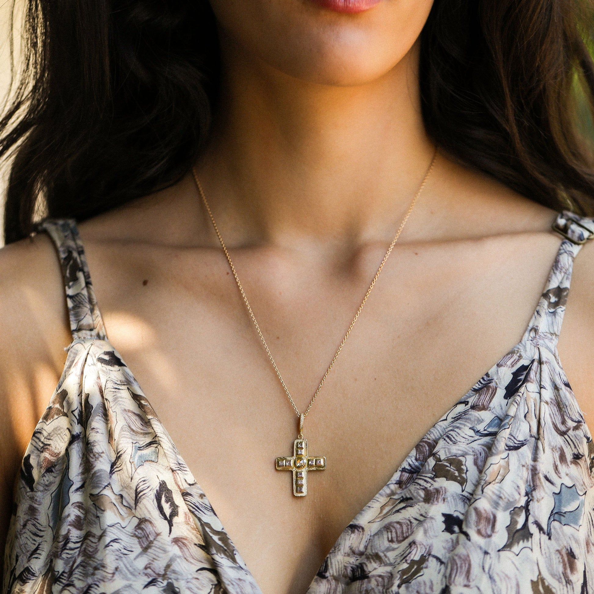 close up of a girl wearing a diamond cross necklace with hand engraving.
