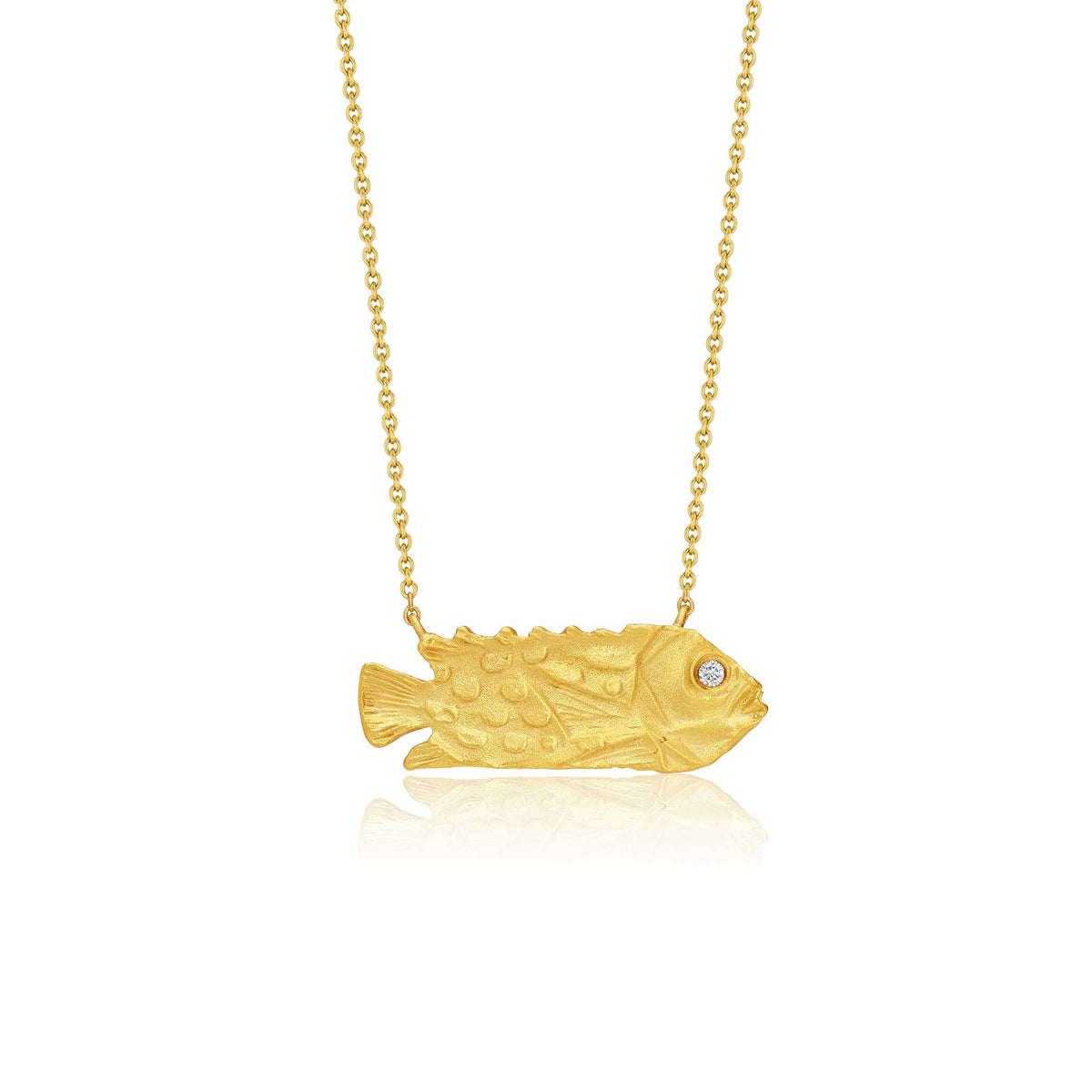 A gold fish-shaped pendant gold necklace with a small diamond gemstone in one eye, suspended from a delicate gold chain against a white background.