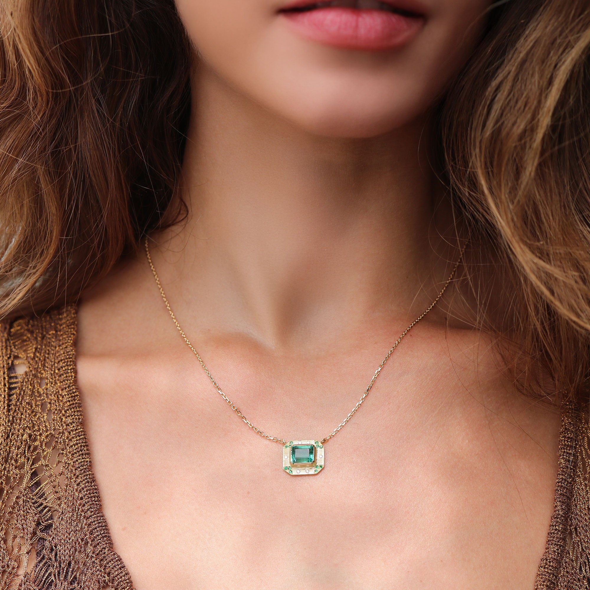 Model wearing 18k gold emerald necklace with hand engraving, emerald and diamond pave from Los Angeles designer Brooke Gregson fine jewelry handmade in London