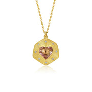 A gold pendant necklace featuring a hand engraved, shield-like gold pendant with a central heart-shaped pink tourmaline gemstone and small diamond accent stones, suspended from a delicate gold chain against a white background.