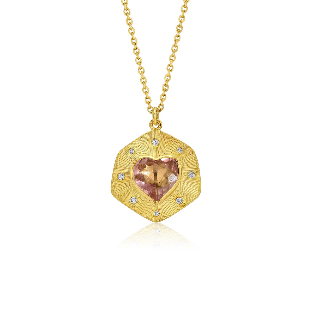 A gold pendant necklace featuring a hand engraved, shield-like gold pendant with a central heart-shaped pink tourmaline gemstone and small diamond accent stones, suspended from a delicate gold chain against a white background.