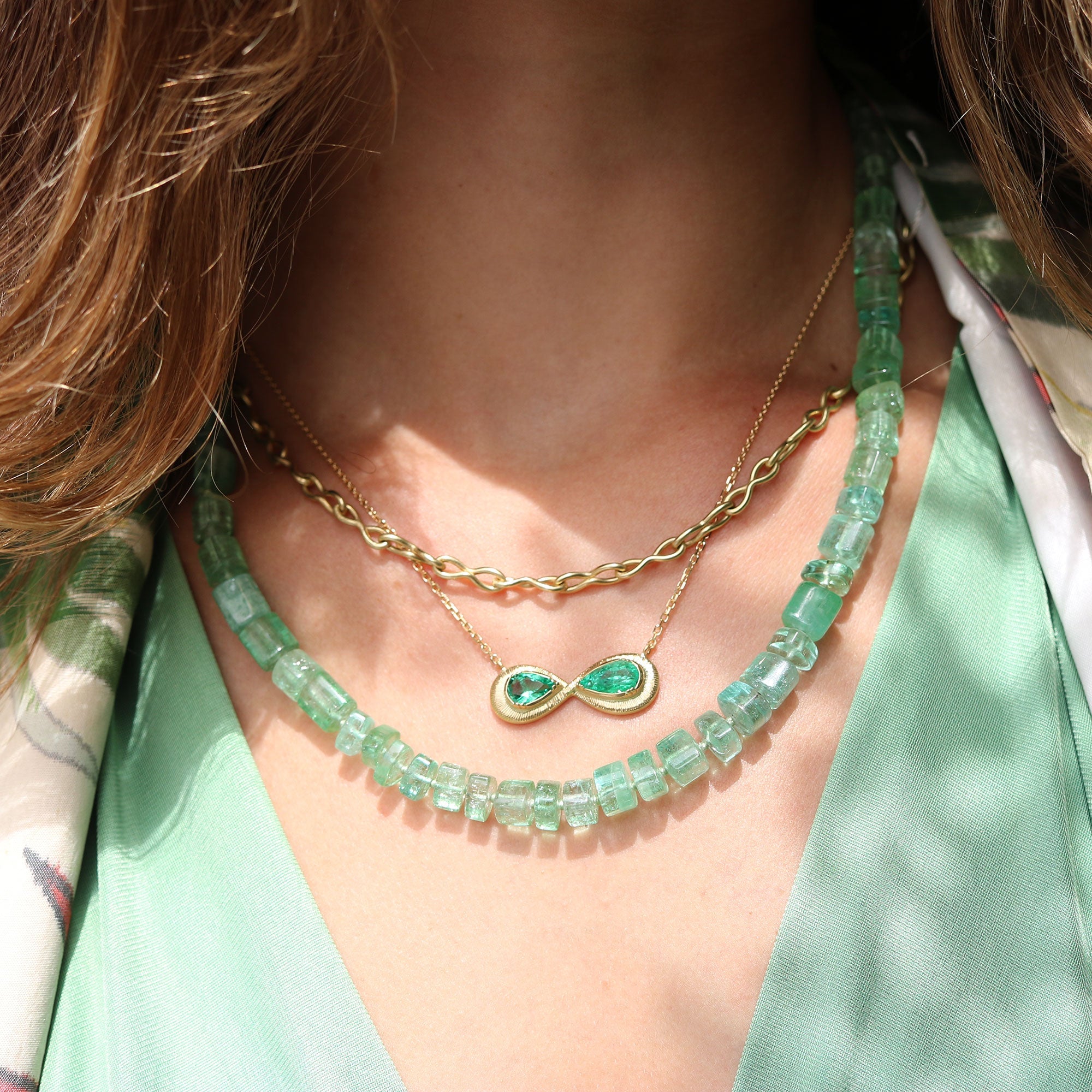 Model wearing One of a kind 18k gold hand engraved Emerald Infinity necklace from Los Angeles designer Brooke Gregson,fine jewelry handmade in London.