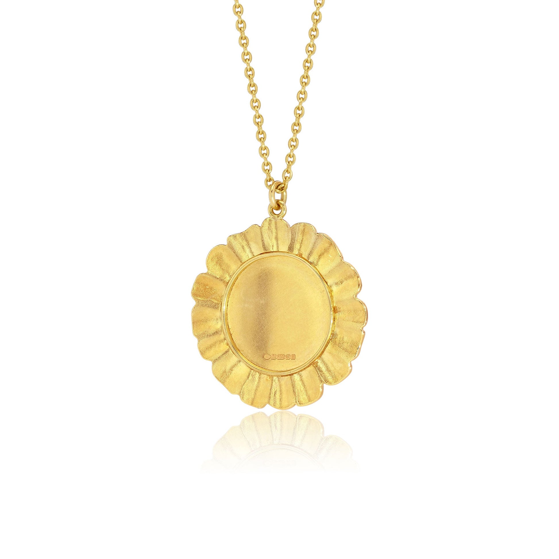 The back of a gold pendant necklace with a textured, scalloped circular frame surrounding a smooth oval center, suspended from a delicate gold chain on a white background with a soft reflection below.