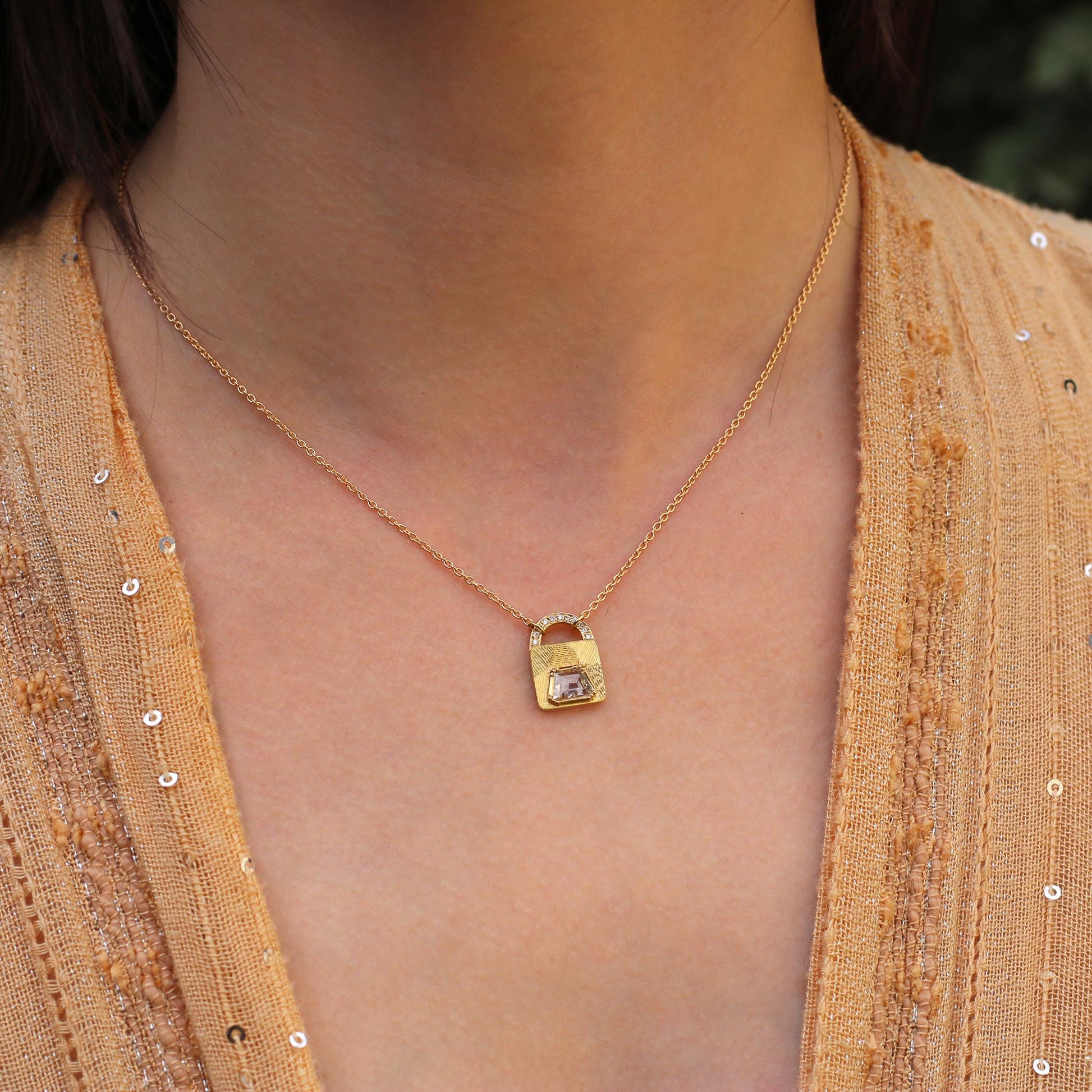 Model wearing one of a kind 18k gold necklace with padlock-shaped pendant, featuring white diamond, hand engraving, and diamond pave from Los Angeles jewelry designer Brooke Gregson.