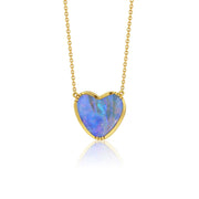 A heart-shaped boulder opal pendant necklace in a 18k yellow gold bezel setting on a delicate gold chain, shown against a solid white background with a soft reflection below.