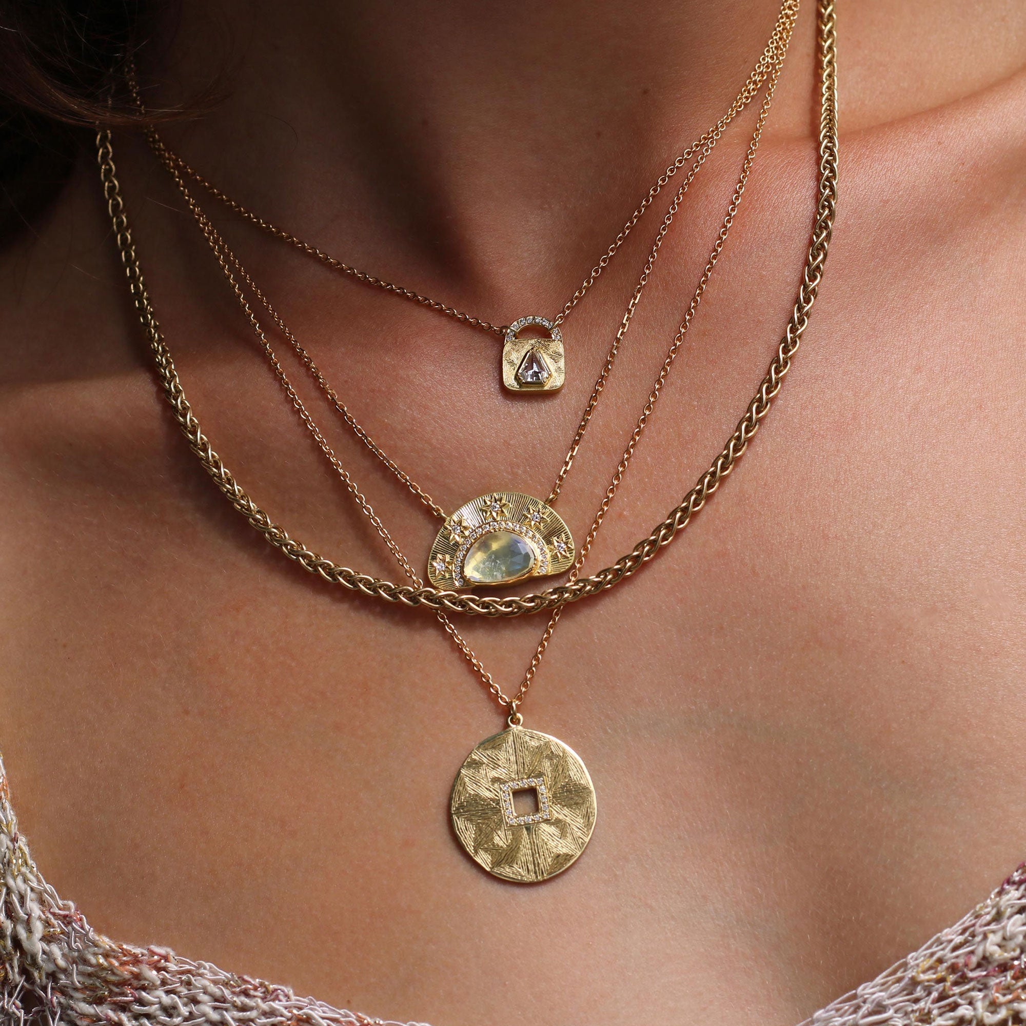 woman wearing a stack of necklaces. One of them is a hera mandala engraved circular pendant necklace.