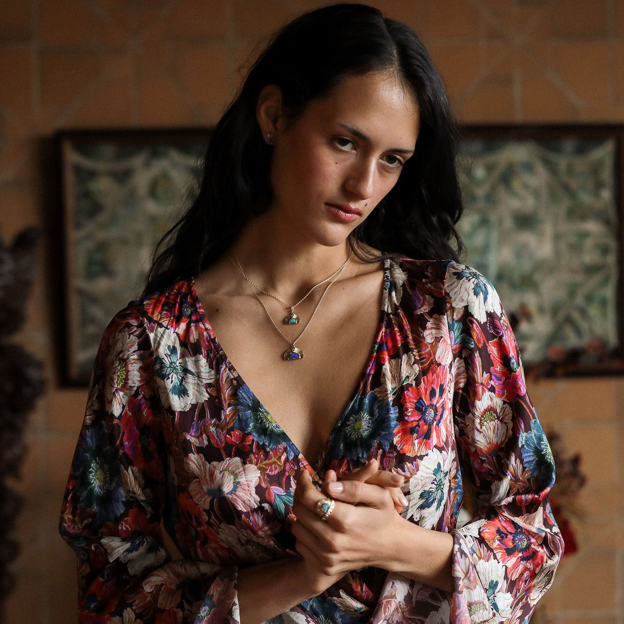 Woman wearing a colorful floral dress with a patterned background and opal necklaces on inn 18k gold.