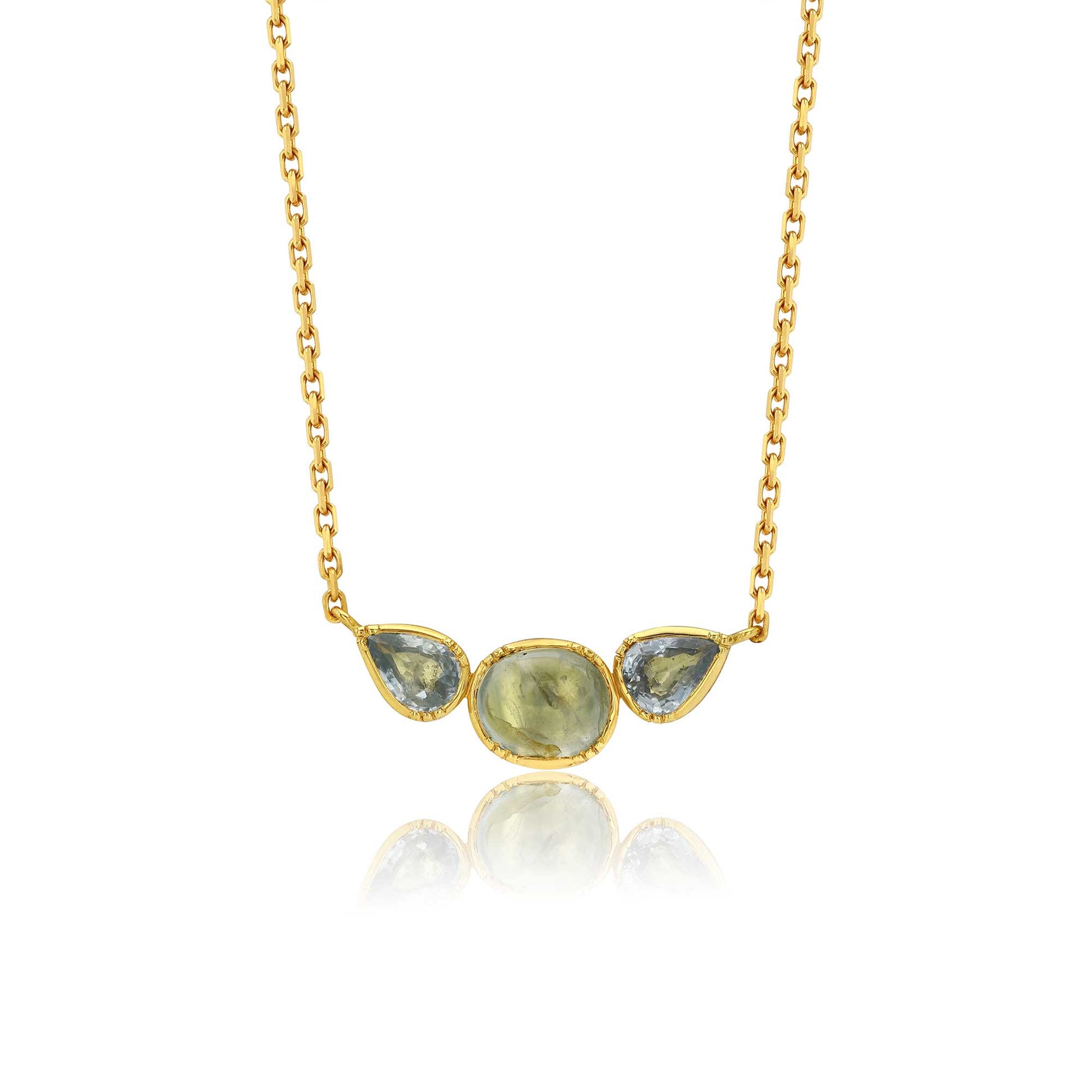 A gold chain necklace featuring a pendant with three teardrop-shaped light blue-green sappphire gemstones in a gold bezel setting, displayed against a white background with a soft reflection below.