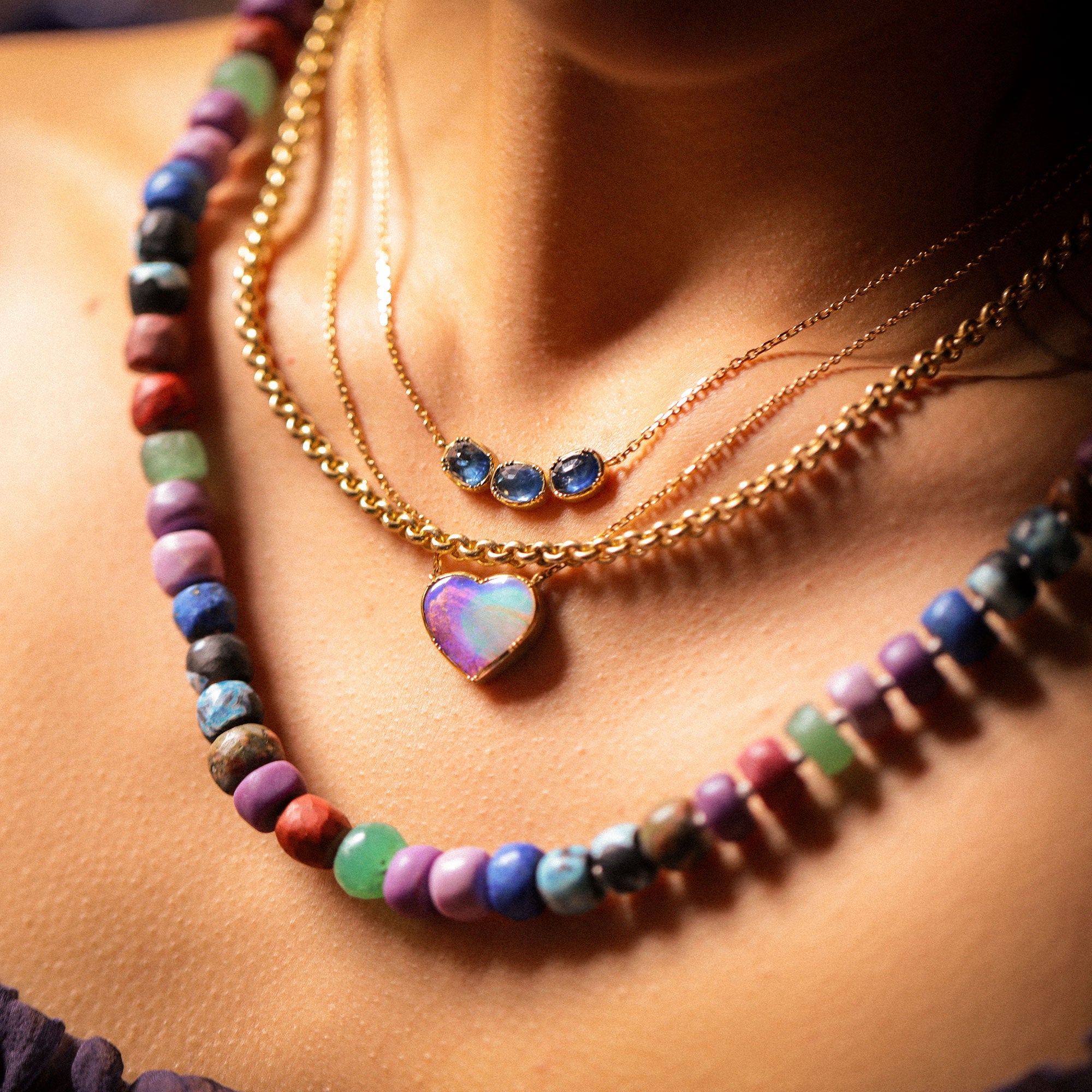 Colorful beaded necklace with a heart-shaped pendant on a person's neck.
