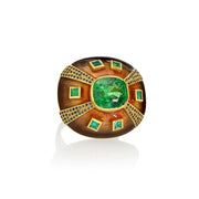 Decorative ring with green tsavorites and emeralds and blue sapphires with enameling and engraving on a white background.