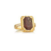 Gold ring with a large raw diamond brown stone and smaller stones on a white background