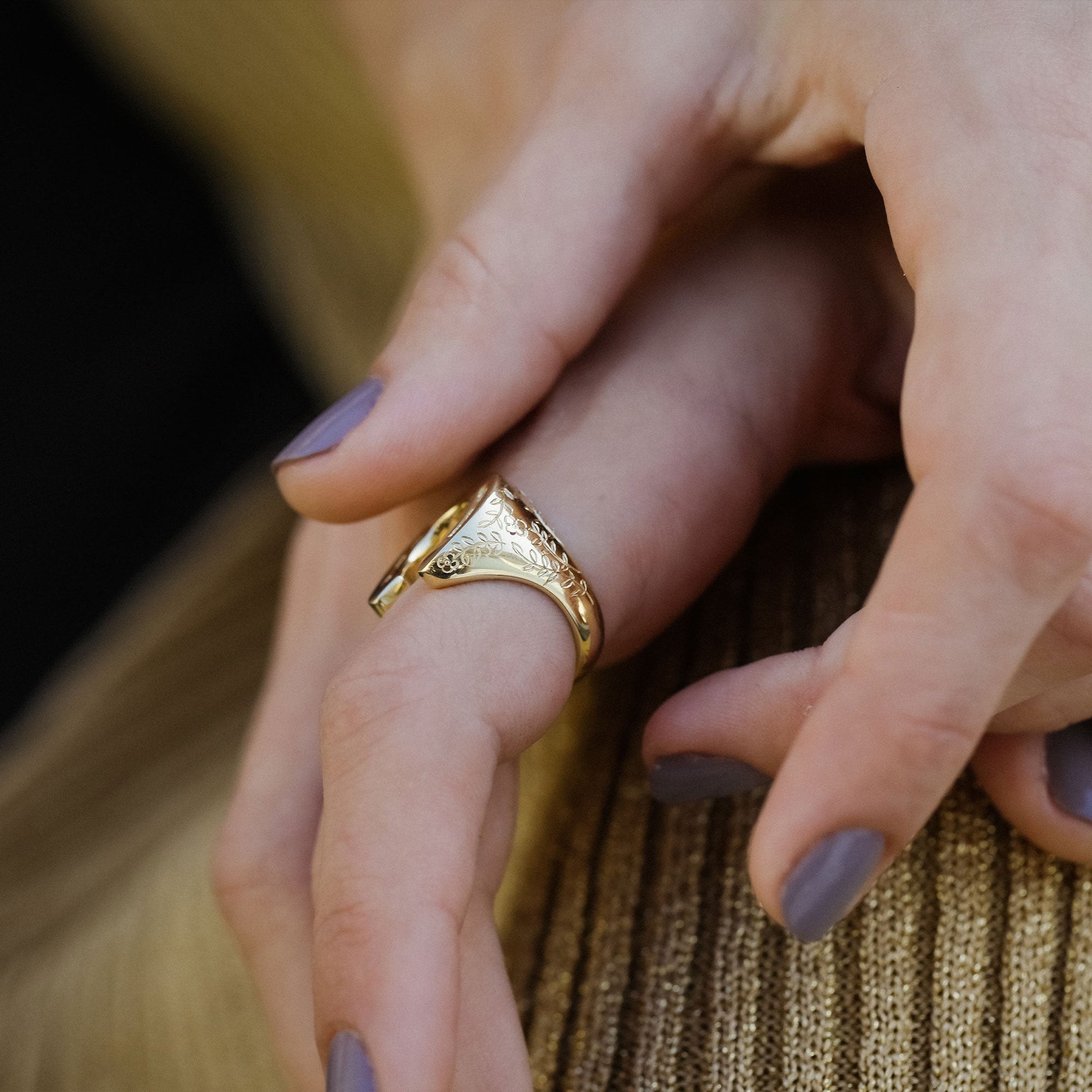 side view of a close up of hand wearing horseshoe ring with white diamonds and hand engraved detailing.