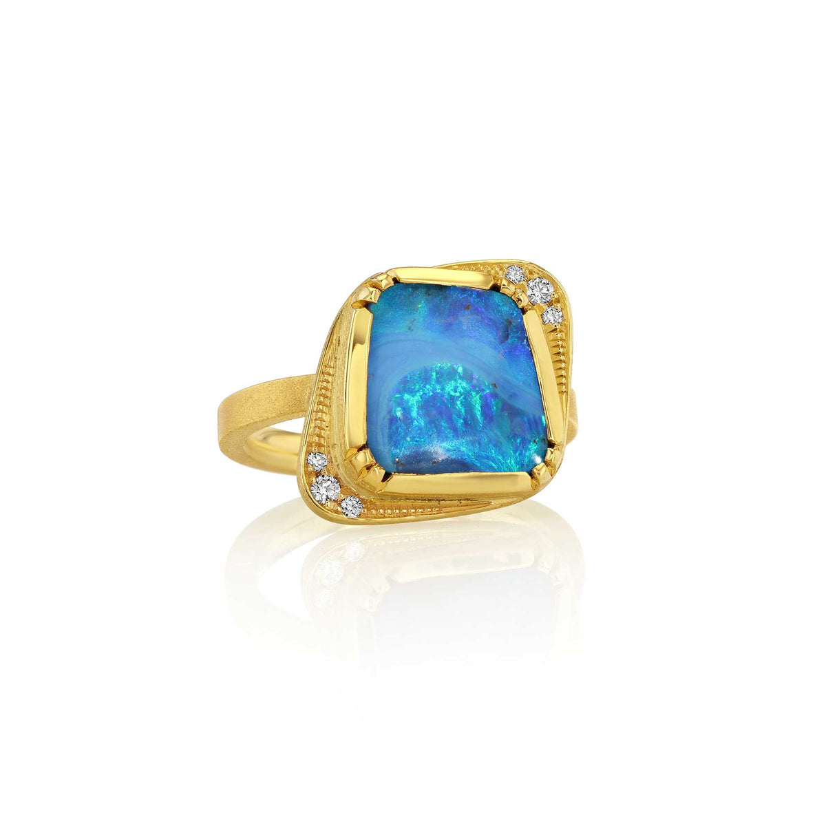 An 18k yellow gold ring featuring a large, irregularly shaped boulder opal stone with vibrant blue, purple, iridescent colors, accented by small diamond gemstones on the outsides, set against a clean white background with a soft reflection. designer by br
