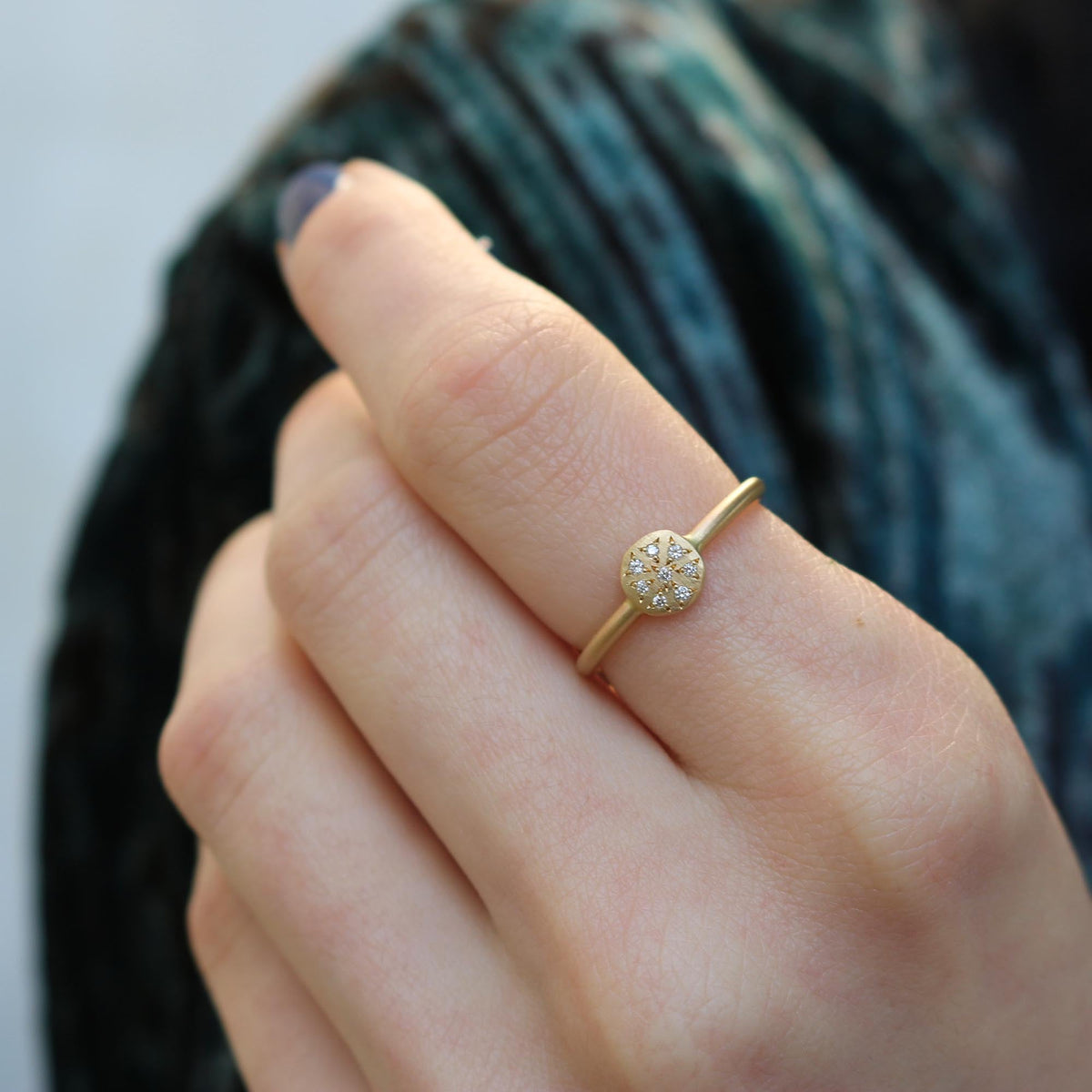 14k gold ring on a persons finger with white diamond accents.