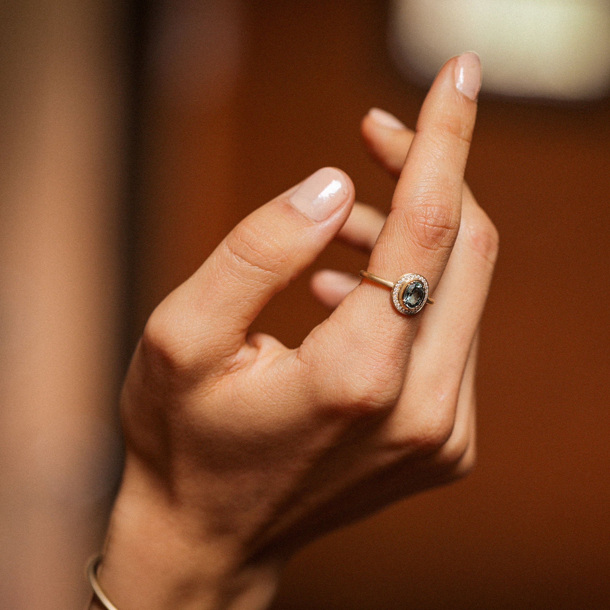 hand wearing a blue sapphire ring with white diamonds encircling it by designer brooke gregson.
