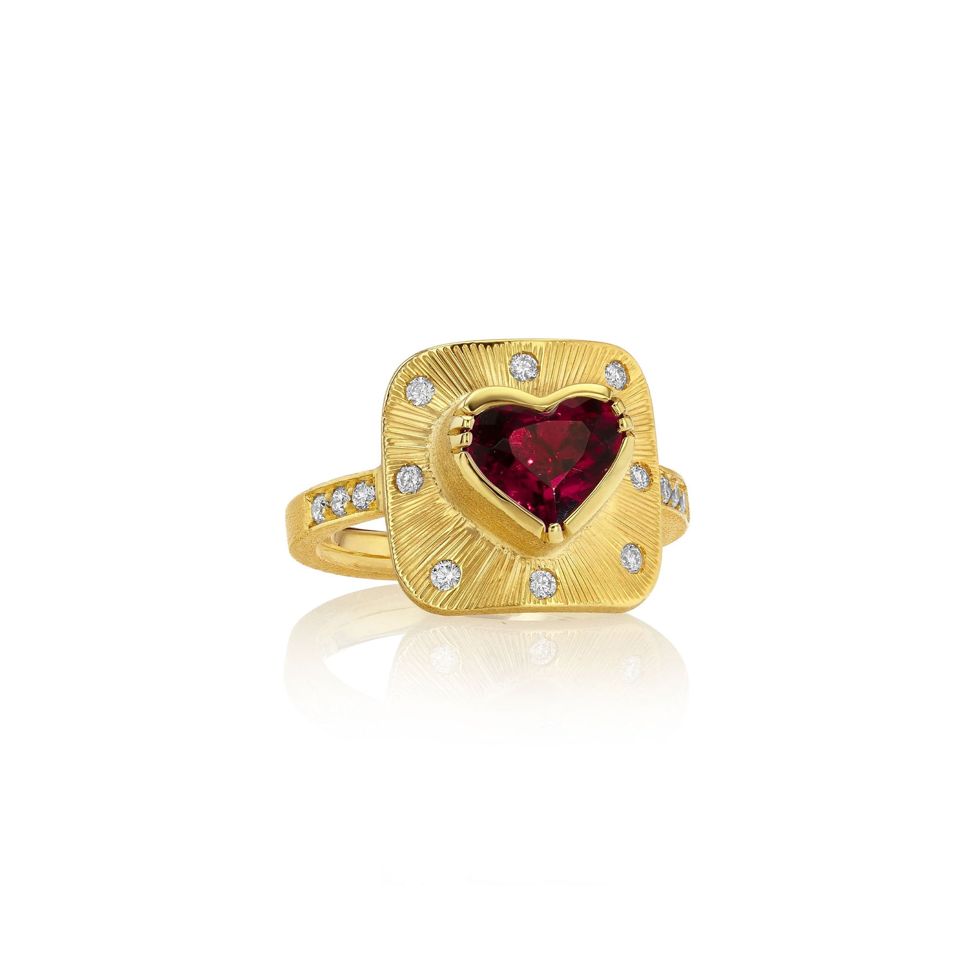 A yellow gold ring featuring a central heart-shaped red tourmaline gemstone surrounded by a square halo of small clear diamond stones, set against a clean white background with a soft reflection.
