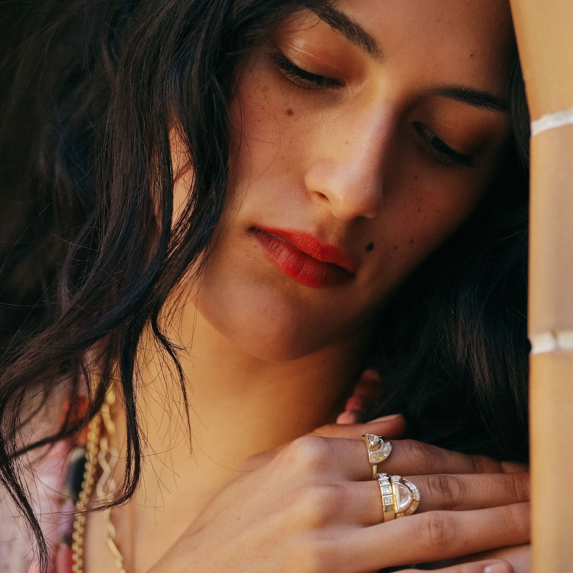 Lifestyle shot of girl wearing multiple 18k gold and white diamond rings designed by Brooke Gregson.