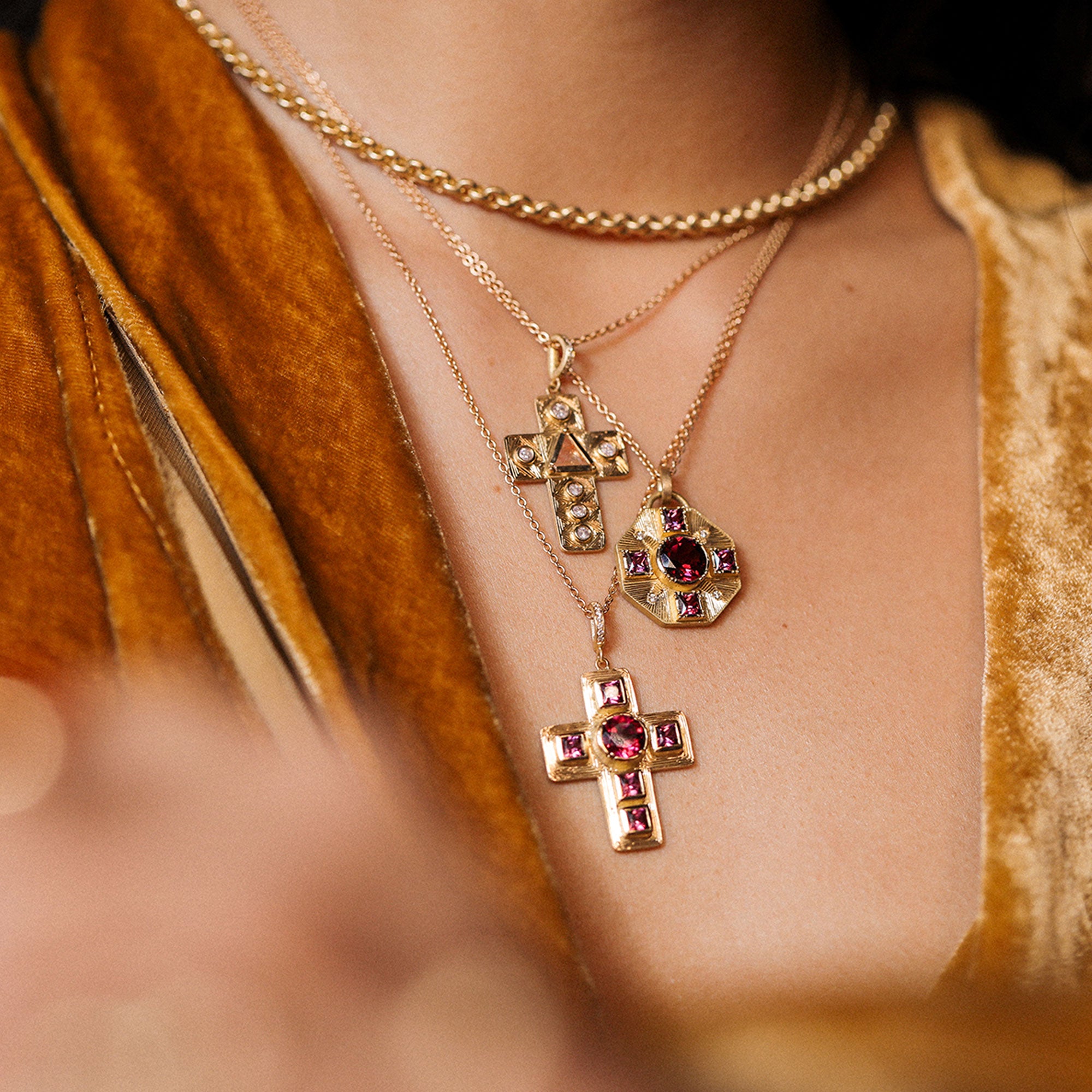Close-up of a person wearing gold necklaces with pendants, blurred background